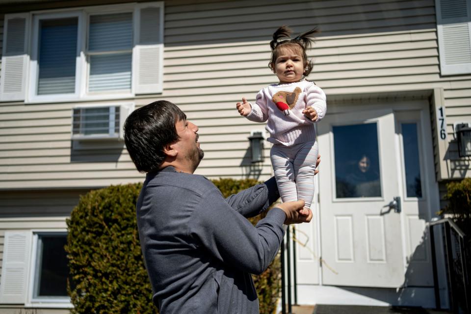 A child stands on a man's palm as he supports her with the other hand,