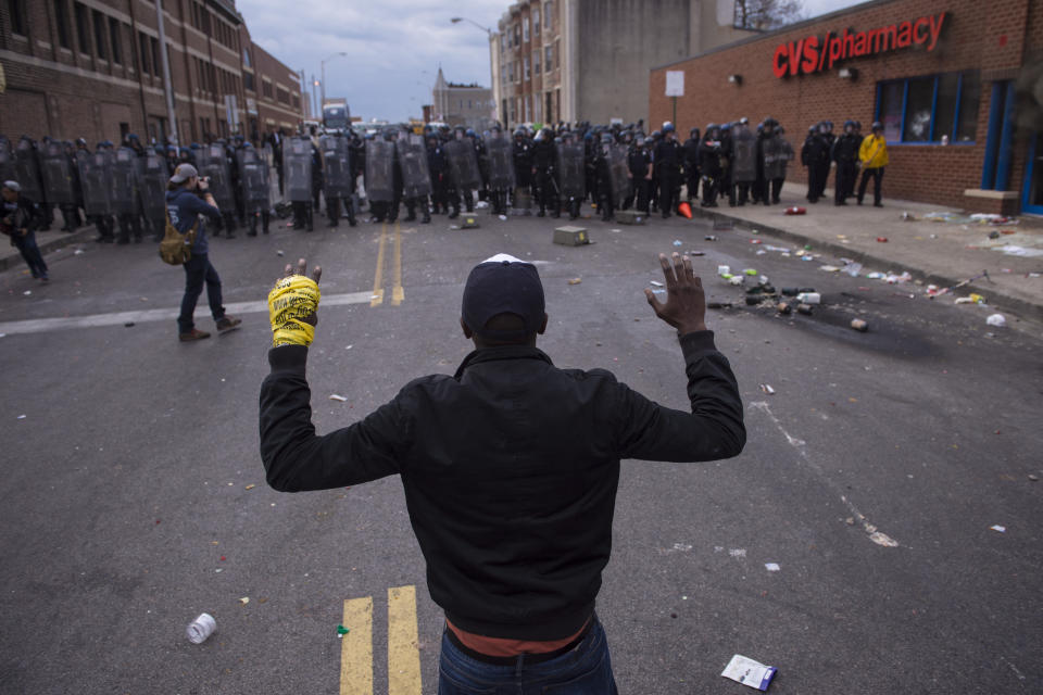 BALTIMORE, MD - APRIL 27: People stand with their hands up as officers move toward them near a CVS pharmacy near West North Avenue and Pennsylvania Avenue during a protest for Freddie Gray in Baltimore, MD on Monday April 27, 2015. Gray died from spinal injuries about a week after he was arrested and transported in a police van. (Photo by Jabin Botsford/The Washington Post via Getty Images)