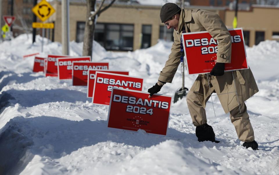 A volunteer plunges campaign signs for Republican Presidential Candidate, Florida Gov. Ron DeSantis into deep snow outside the Chrome Horse Saloon one day before the Iowa caucuses