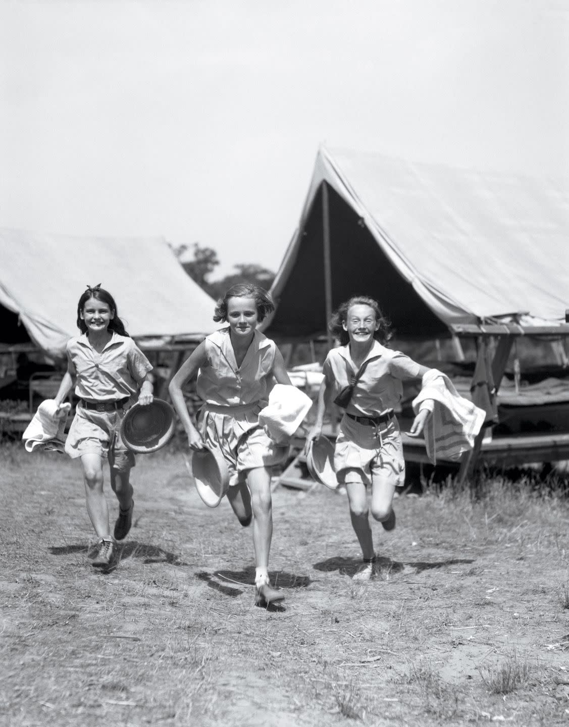 1930s three teen girls wearing camp shorts shirts running from tents while holding towels wash basins photo by h armstrong robertsclassicstockgetty images