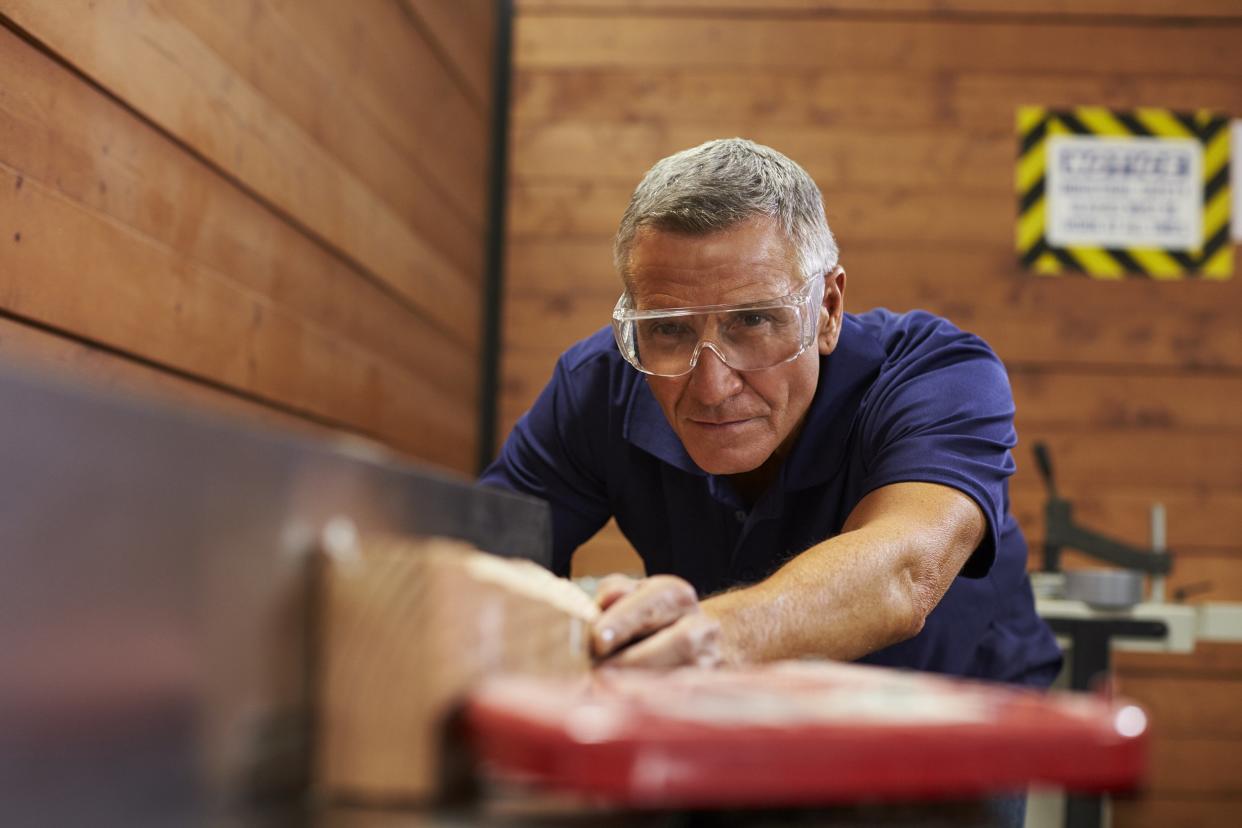 carpenter using plane in woodworking wood shop