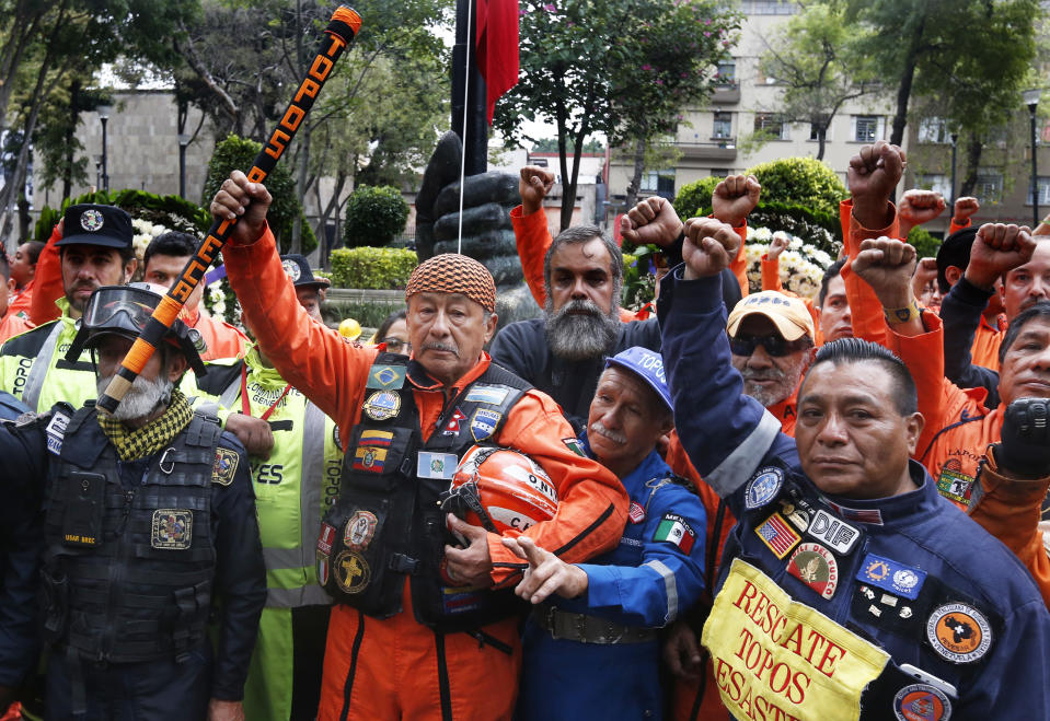 Rescue workers stand with with raised fists and in silence, in front of a 1985 earthquake memorial during a ceremony marking that quake's 33rd anniversary and last year's 7.1 magnitude earthquake, in Mexico City, Wednesday, Sept. 19, 2018. The rescue workers, known as "topos," are a voluntary civil brigade, who were created during the 1985 earthquake that left at least 9,500 dead. (AP Photo/Marco Ugarte)
