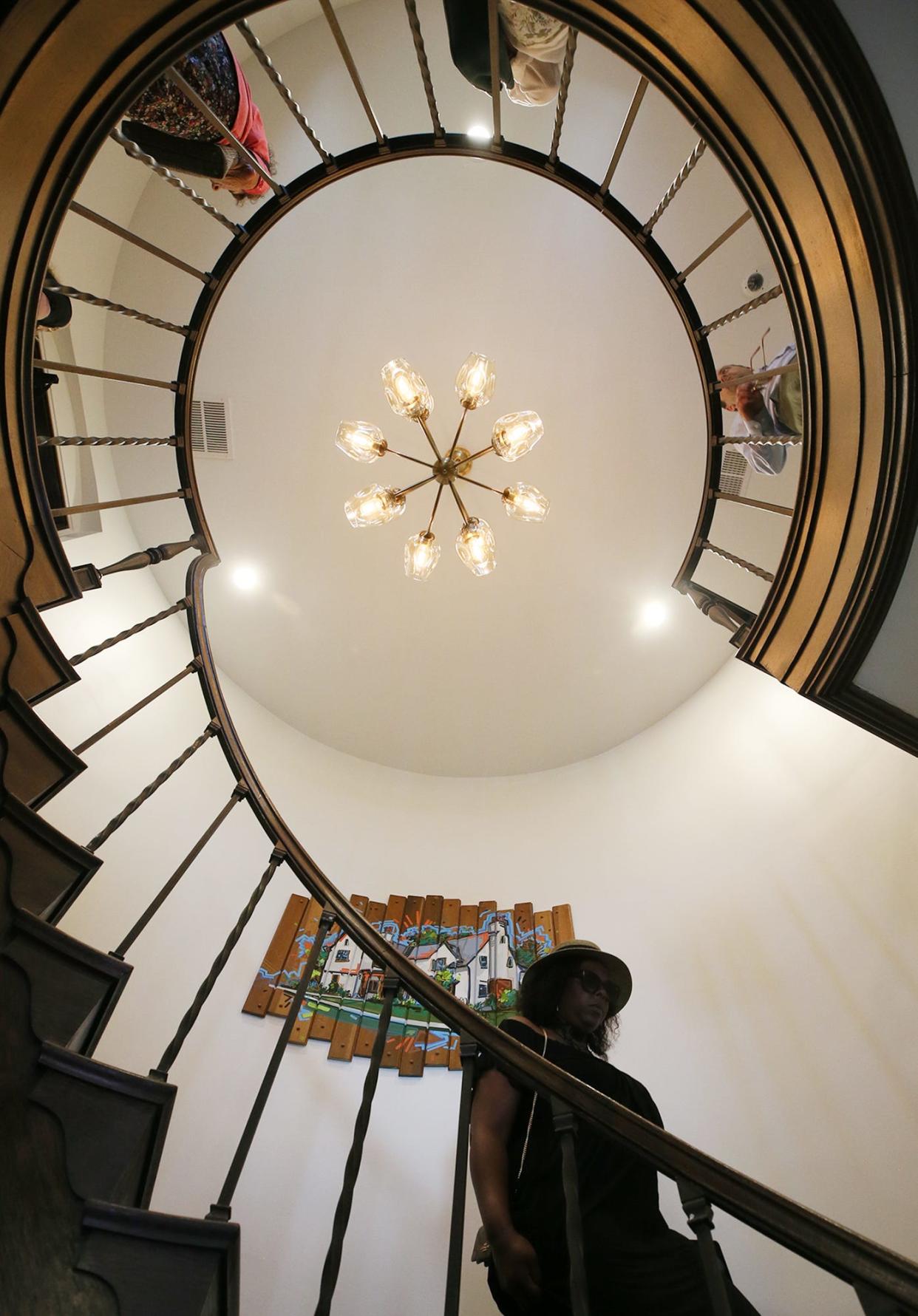 Visitors walk down the spiral staircase as they tour the Summit County Land Bank's new offices at the former home of John S. Knight after the grand opening ceremony in Akron on Friday.
