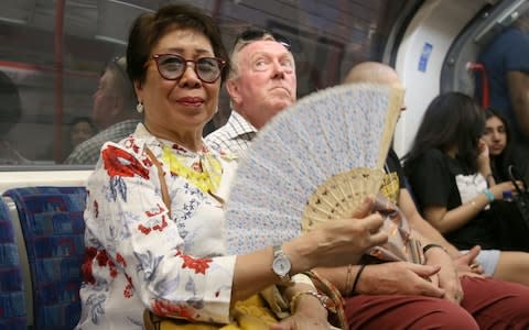 Hot commuters on London's Central line, try to cool down - Credit: SWNS.com 