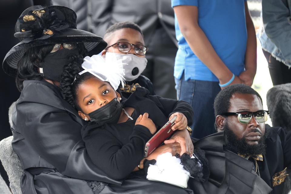 Widow Cathy Beck holds her grandchildren Ivy Monroe, 7, and R.J. Miller, 11, with son Ivory Beck Jr., right, by her side as they watch the honor guard fold the flag of Ivory Beck Sr. during funeral services at Memorial Park South Woods on May 29, 2021.