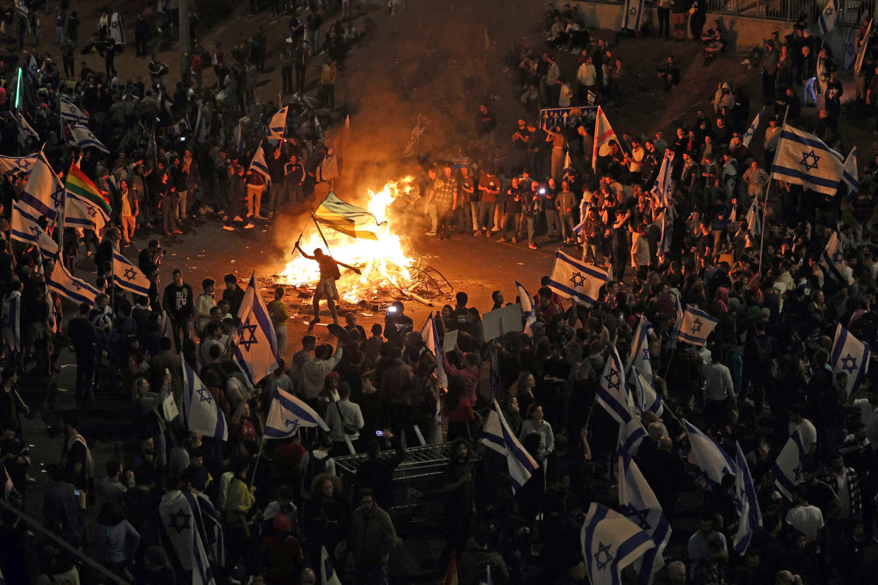 Protesters block a road and hold national flags as they gather around a bonfire during a rally against the Israeli government's judicial reform in Tel Aviv on March 27, 2023.  (Ahmad Gharabli  / AFP - Getty Images)