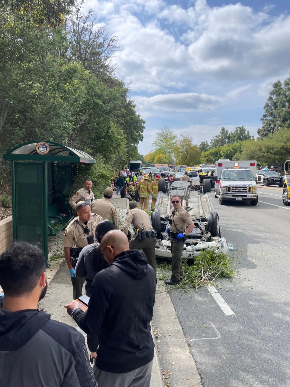 Ventura County Sheriff's deputies and other bystanders gather near the scene of a fatal crash near Westlake High School in Thousand Oaks April 18, 2023. Freshman Wesley Welling was killed and three other students injured.