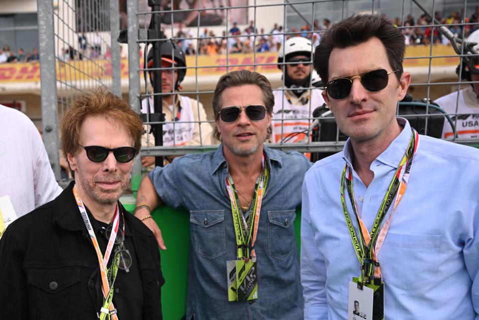 (L-R) US film producer Jerry Bruckheimer, US actor Brad Pitt and US film director Joseph Kosinski await the start of the Formula One United States Grand Prix, at the Circuit of the Americas in Austin, Texas, on October 23, 2022. (Photo by Patrick T. FALLON / AFP) (Photo by PATRICK T. FALLON/AFP via Getty Images)