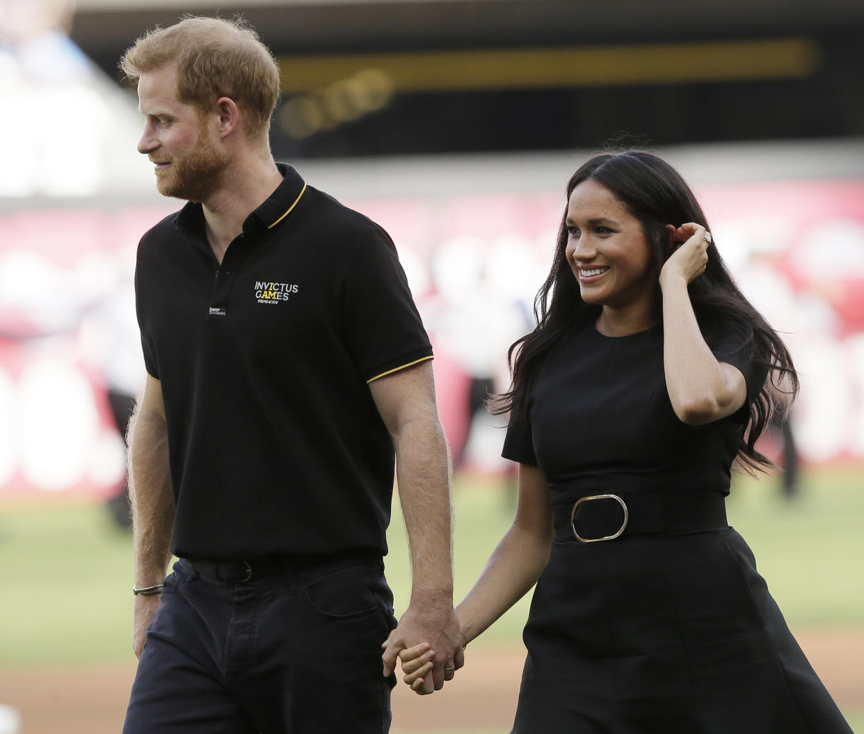 Britain's Prince Harry, left, and Meghan, Duchess of Sussex, walk off the field before a baseball game between the Boston Red Sox and the New York Yankees, Saturday, June 29, 2019, in London. Major League Baseball makes its European debut game today at London Stadium. (AP Photo/Tim Ireland)