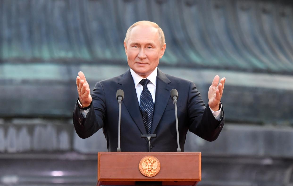 Russian President Vladimir Putin gestures while delivering a speech.