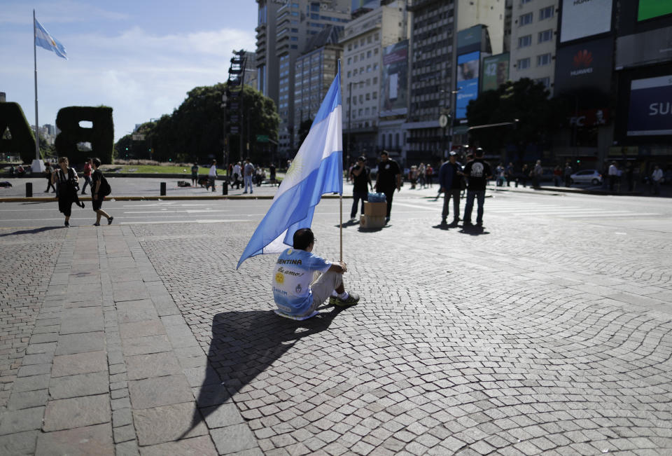 Un hombre sostiene una bandera de Argentina mientras se sienta en la avenida 9 de Julio en Buenos Aires, Argentina, el jueves 6 de abril de 2017. Un paro general, el primero durante la gestión del presidente Mauricio Macri, forzó a que los servicios de trasporte no trabajaran el jueves. (AP Foto/ Natacha Pisarenko))