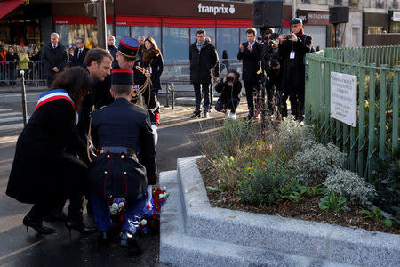 French President Emmanuel Macron (2ndL) and Paris Mayor Anne Hidalgo lay a wreath of flowers in front of a commemorative plaque next to the "A La Bonne Biere" cafe and the Rue de la Fontaine au Roi street, in Paris, France, November 13, 2017, during a ceremony held for the victims of the Paris attacks which targeted the Bataclan concert hall as well as a series of bars and killed 130 people. REUTERS/Philippe Wojazer