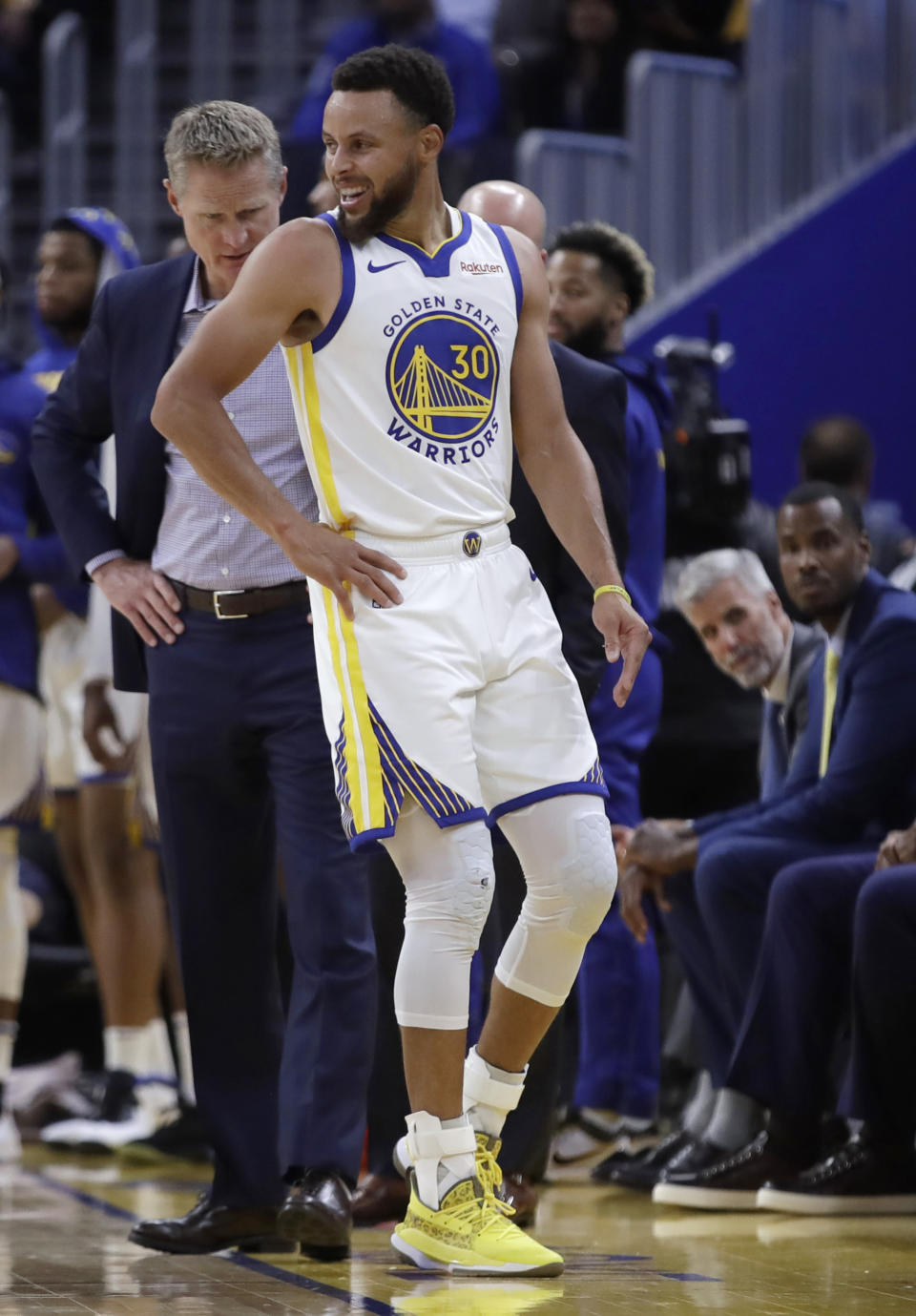 Golden State Warriors coach Steve Kerr, left, observes Stephen Curry (30) after Phoenix Suns' Aron Baynes fell onto him during the second half of an NBA basketball game Wednesday, Oct. 30, 2019, in San Francisco. Curry left the game. (AP Photo/Ben Margot)