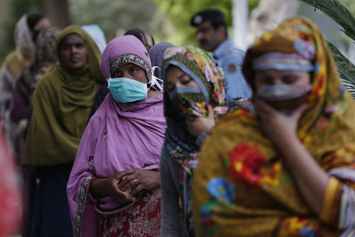 Women in Islamabad, Pakistan, wait to receive cash from a government program for families in need