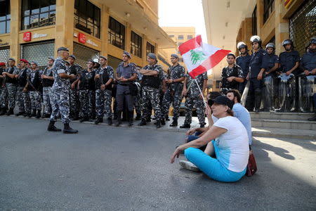 Protestors carry a Lebanese flag in front of riot police at one of the entrances to the environment ministry in downtown Beirut, Lebanon September 1, 2015. REUTERS/Aziz Taher