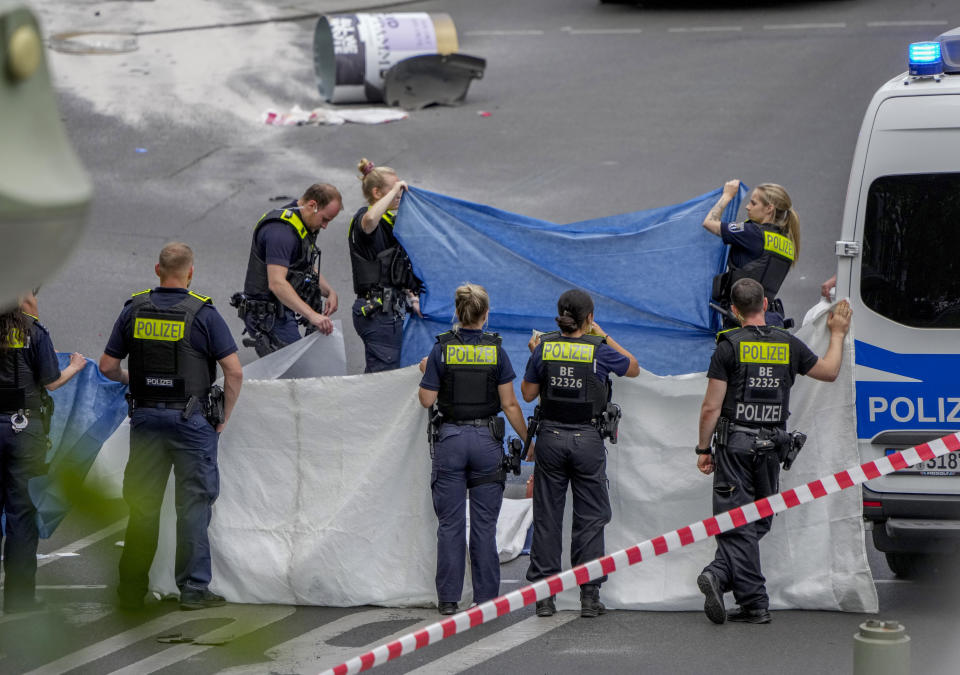Police officers cover a dead body after a car crashed into a crowd of people in central Berlin, Germany, Wednesday, June 8, 2022. (AP Photo/Michael Sohn)