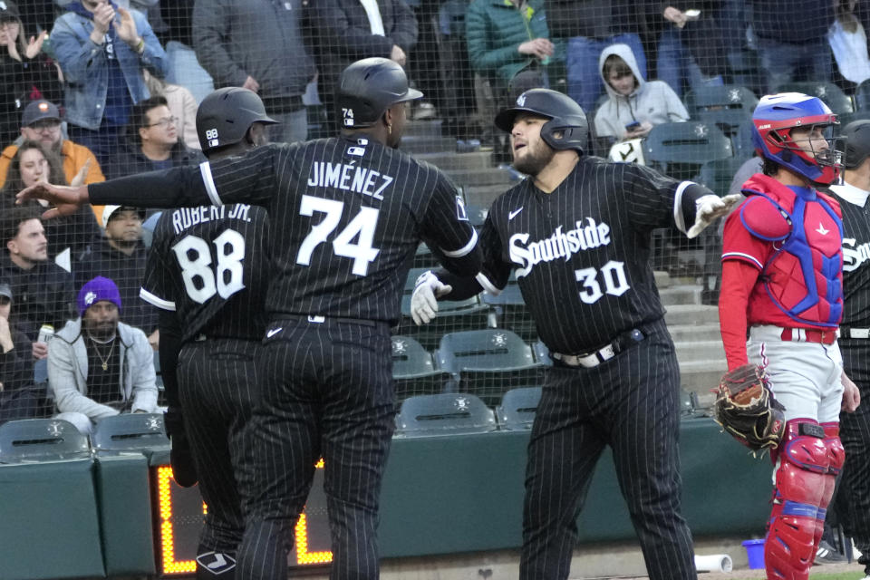 Chicago White Sox's Jake Burger (30) celebrates his three-run home run off Philadelphia Phillies starting pitcher Bailey Falter with Luis Robert Jr. (88) and Eloy Jimenez during the first inning in the second game of a baseball doubleheader Tuesday, April 18, 2023, in Chicago. (AP Photo/Charles Rex Arbogast)