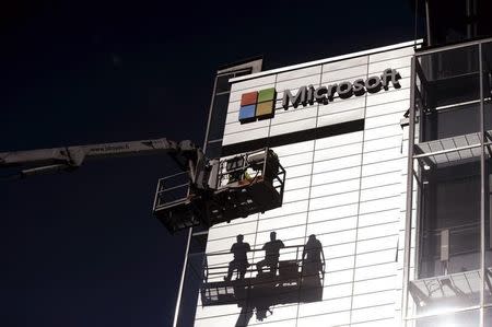 Workers install the logo of U.S. technology giant Microsoft on the wall of Nokia's former headquarters in Espoo April 26, 2014. REUTERS/Mikko Stig/Lehtikuva