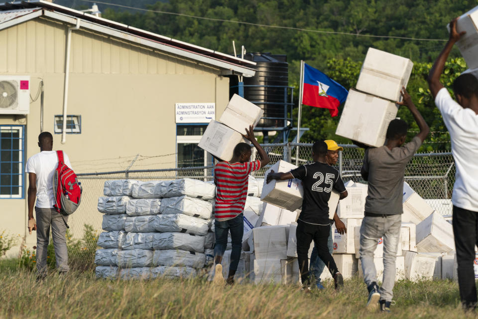 Haitian aid workers move aid boxes after unloading a VM-22 Osprey at Jeremie Airport, Saturday, Aug. 28, 2021, in Jeremie, Haiti. The VMM-266, "Fighting Griffins," from Marine Corps Air Station New River, from Jacksonville, N.C., are flying in support of Joint Task Force Haiti after a 7.2 magnitude earthquake on Aug. 22, caused heavy damage to the country. (AP Photo/Alex Brandon)