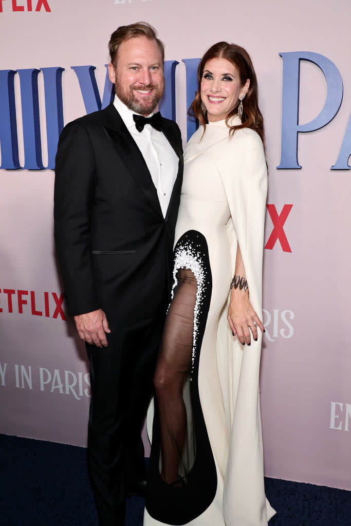 Josh Stamberg in a black tuxedo and Kate Walsh in a white dress with black detailing attend a Netflix event for "Emily in Paris."