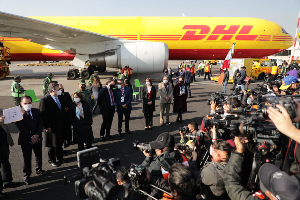 The press photographs officials as the first shipment of the Pfizer COVID-19 vaccine to Mexico is pulled away, top right, after being unloaded from a DHL cargo plane at the Benito Juarez International Airport in Mexico City, Wednesday, Dec. 23, 2020. (AP Photo/Eduardo Verdugo)