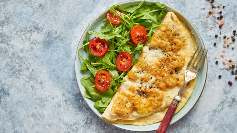 Traditional omelet with cheese next to salad greens