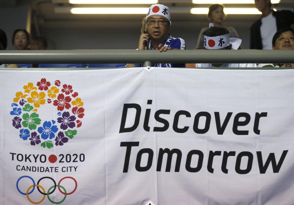 A man uses a mobile phone above a campaign sign for Tokyo to host the 2020 Olympic and Paralympic Games during a public viewing event in Tokyo September 7, 2013. The IOC will elect the winning city from candidates Tokyo, Madrid, and Istanbul on Saturday afternoon at their 125th Session in the Argentine capital. REUTERS/Toru Hanai (JAPAN - Tags: SPORT OLYMPICS)