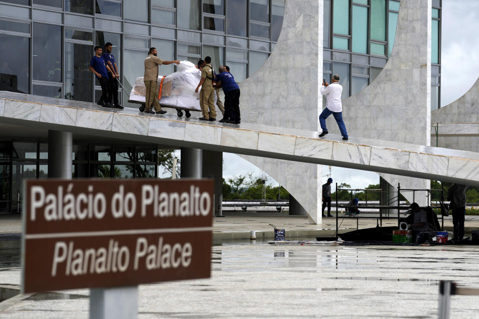 Movers transport items out of Planalto presidential palace as workers prepare the ramp for the inauguration ceremony in Brasilia, Brazil, Friday, Dec. 16, 2022. President-elect Luiz Inácio Lula da Silva will be sworn-in on Jan. 1, 2023. (AP Photo/Eraldo Peres)