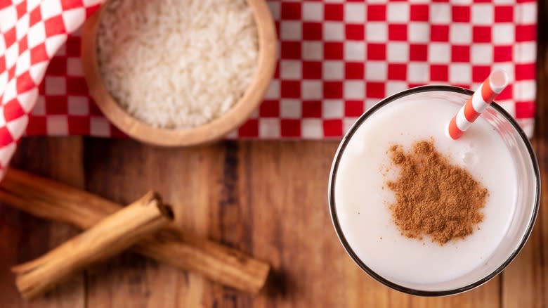 Overhead shot of horchata, bowl of rice, and cinnamon sticks