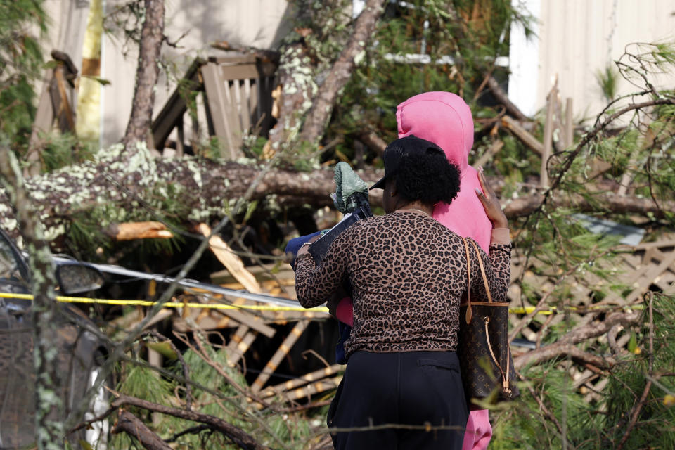 Family members console each other outside a damaged mobile home, Wednesday, Nov. 30, 2022, in Flatwood, Ala., the day after a severe storm swept through the area. Two people were killed in the Flatwood community just north of the city of Montgomery. (AP Photo/Butch Dill)