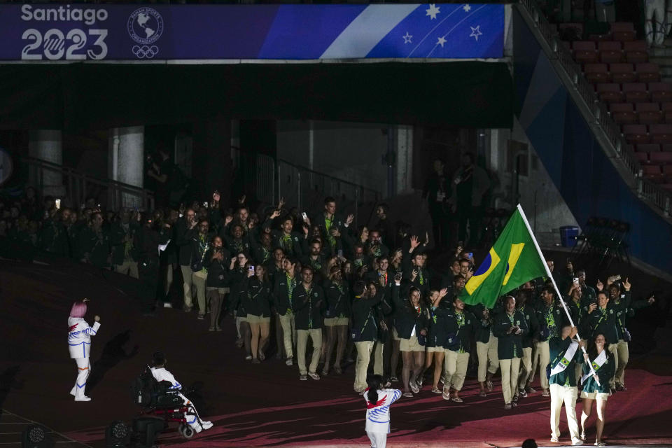 Luisa Stefani and Fernando Scheffer of Brazil carry their country's flag during the opening ceremony of the Pan American Games at the National Stadium in Santiago, Chile, Friday, Oct. 20, 2023. (AP Photo/Esteban Felix)