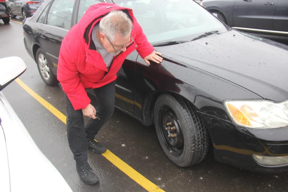 Paul Finlayson inspecting the repairs made to his damaged car. He had to pay $350 out of pocket to replace two tires due to damage caused by a pothole.