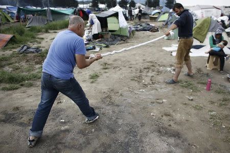 Refugees squeeze a wet blanket after heavy rainfall at a makeshift camp for migrants and refugees at the Greek-Macedonian border near the village of Idomeni, Greece, May 22, 2016. REUTERS/Kostas Tsironis