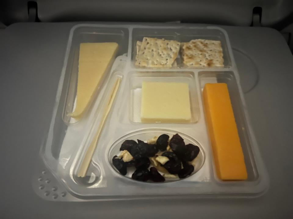 The cheese tray with cheese, crackers, and raisins.