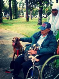 A participant petting a dog while cradling another at the event in Bandar Utama. – Pic used with permission, October 19, 2014.