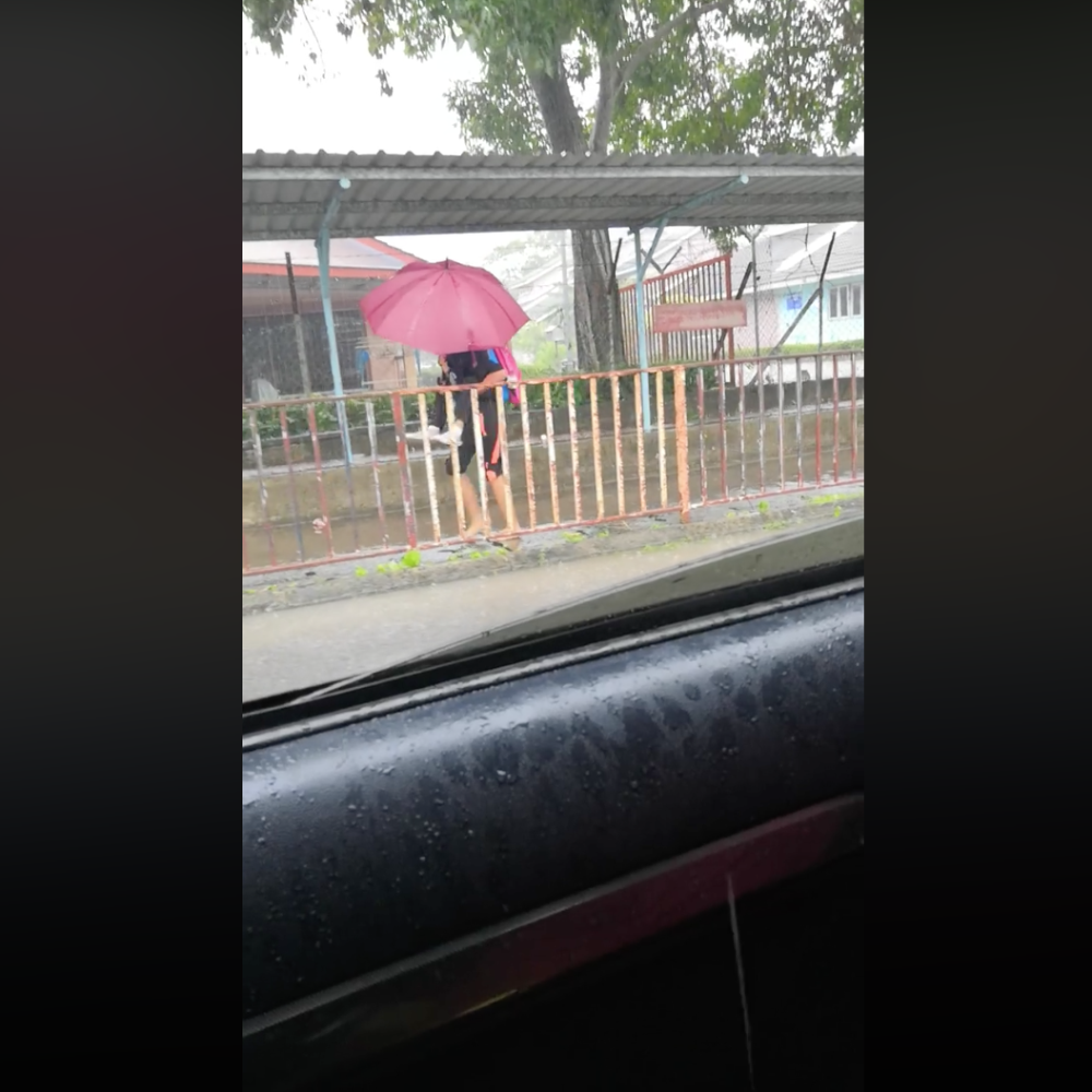 The student braved the heavy rain to help her schoolmate with autism get to class safe and dry. — Screengrab from Facebook/Maslika Bt Ramli