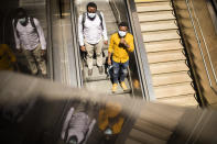 Two men, wearing face masks to protect against the spread of coronavirus, take an escalator into Schuman metro station during the partial lifting of coronavirus, COVID-19, lockdown regulations in Brussels, Thursday, May 28, 2020. (AP Photo/Francisco Seco)