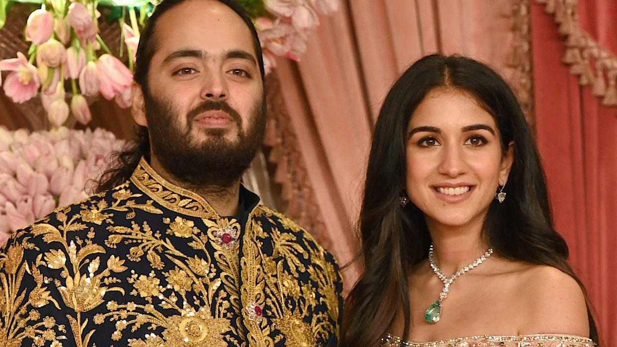 Anant Ambani in a gold jacket with Radhika Merchant in an off the shoulder top