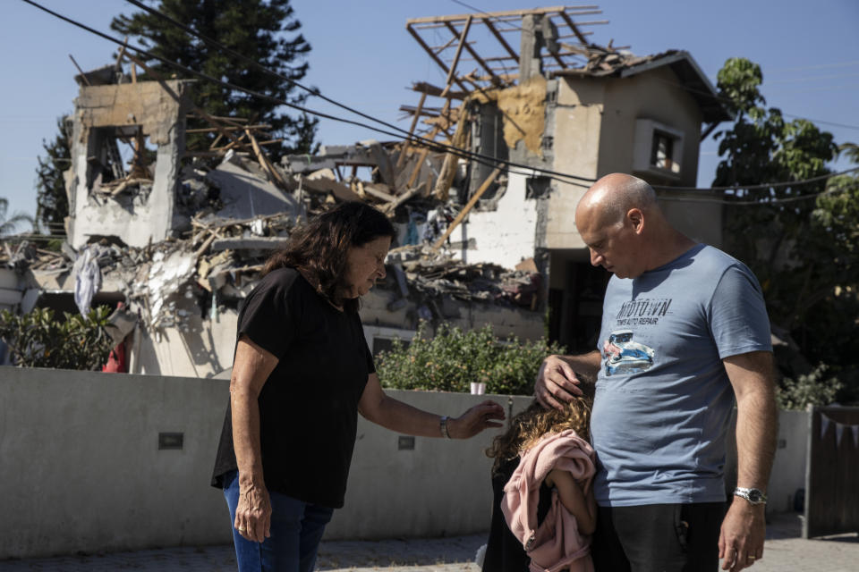 A young girl is comforted by her father next to a house damaged by a rocket fired from the Gaza Strip, in Yehod, central Israel, Wednesday, May 12, 2021. The house was hit on May 11, as barrage of rockets fired from the Gaza Strip toward central Israel. (AP Photo/Heidi Levine)