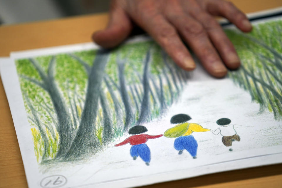 Mitsuyo Hoshino, 86, who lost her parents and siblings to the Great Tokyo Air Raid on March 10, 1945, shows her drawing of her experience during an interview with the Associated Press at the Center for the Tokyo Raids and War Damage in Tokyo Tuesday, July 28, 2020. In Japan, war orphans were punished for surviving. They were bullied. They were called trash, sometimes rounded up by police and put in cages. Some were sent to institutions or sold for labor. They were targets of abuse and discrimination. Now, 75 years after the war's end, some are revealing their untold stories of recovery and pain, underscoring Japan’s failure to help its own people. (AP Photo/Eugene Hoshiko)