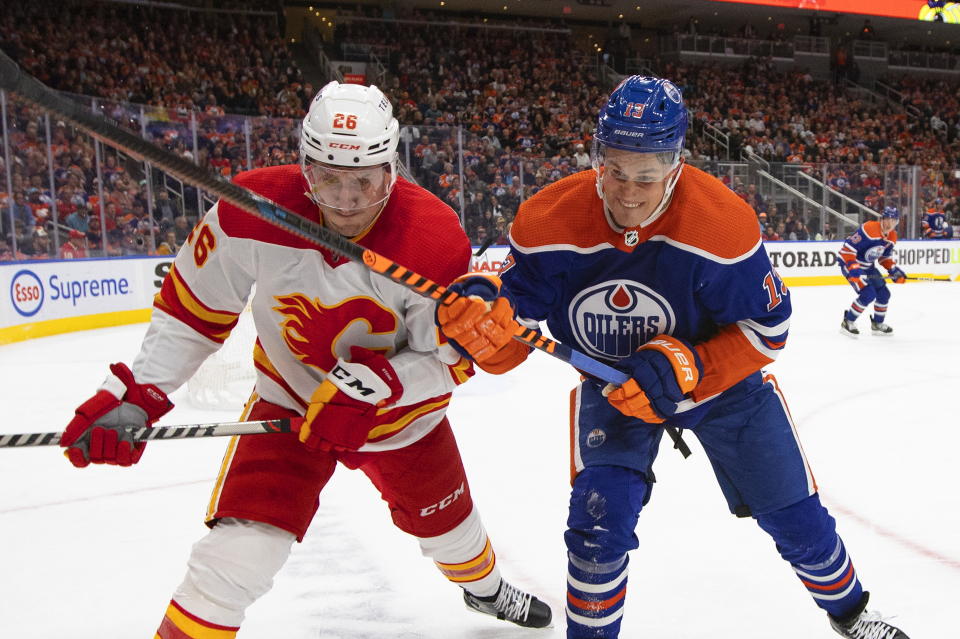 Calgary Flames' Michael Stone (26) and Edmonton Oilers' Jesse Puljujarvi (13) vie for the puck during the second period of an NHL hockey game Saturday, Oct. 15, 2022, in Edmonton, Alberta. (Jason Franson/The Canadian Press via AP)