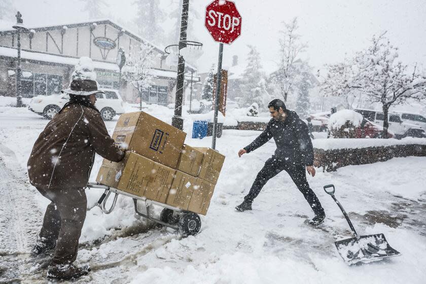 Big Bear, CA, Tuesday, February 6, 2024 - Saeed Fardin, part owner of Superhero Toys n More clears the sidewalk as a shipment of goods is delivered during a snowstorm in Big Bear. (Robert Gauthier/Los Angeles Times)