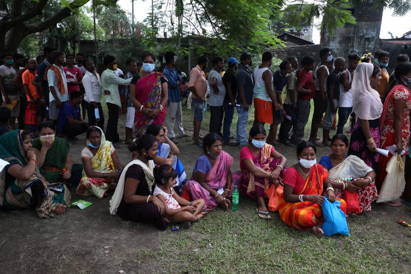People wait in a queue to receive a dose of COVISHIELD vaccine, outside a vaccination centre in Siliguri