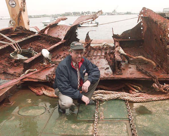 Allan Carlin, general counsel for RMS Titanic Inc., poses for photographers in front of a section of the hull of the RMS Titanic at the Commonwealth Pier in Boston, 21 August. The 20-ton steel piece, which was recovered 10 August from the floor of the Atlantic off Newfoundland 10 miles from the original wreck site, will join the Titanic exhibition underway at the World Trade Center in Boston.     (Photo credit: STUART CAHILL/AFP via Getty Images)