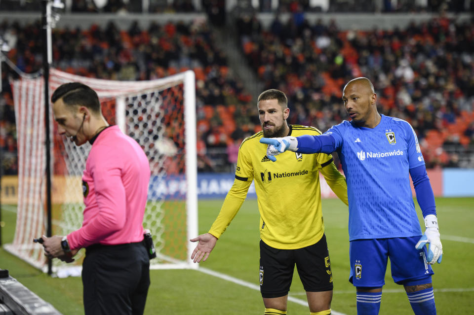Referee Ismir Pekmic, left, checks video footage while Columbus Crew goalkeeper Eloy Room (1) and defender Milos Degenek (5) plead their case during second-half MLS soccer match action against Toronto FC in Toronto, Saturday, March 11, 2023. (Christopher Katsarov/The Canadian Press via AP)
