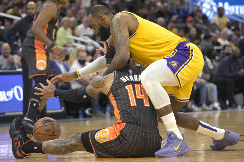 Orlando Magic guard Gary Harris (14) and Los Angeles Lakers forward LeBron James compete for the ball during the first half of an NBA basketball game, Friday, Jan. 21, 2022, in Orlando, Fla. (AP Photo/Phelan M. Ebenhack)