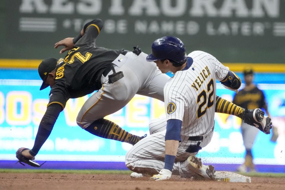 Pittsburgh Pirates' Erik Gonzalez can't handle the throw as Milwaukee Brewers' Christian Yelich slides safely into second for a two-run scoring double during the seventh inning of a baseball game Friday, June 11, 2021, in Milwaukee. (AP Photo/Morry Gash)