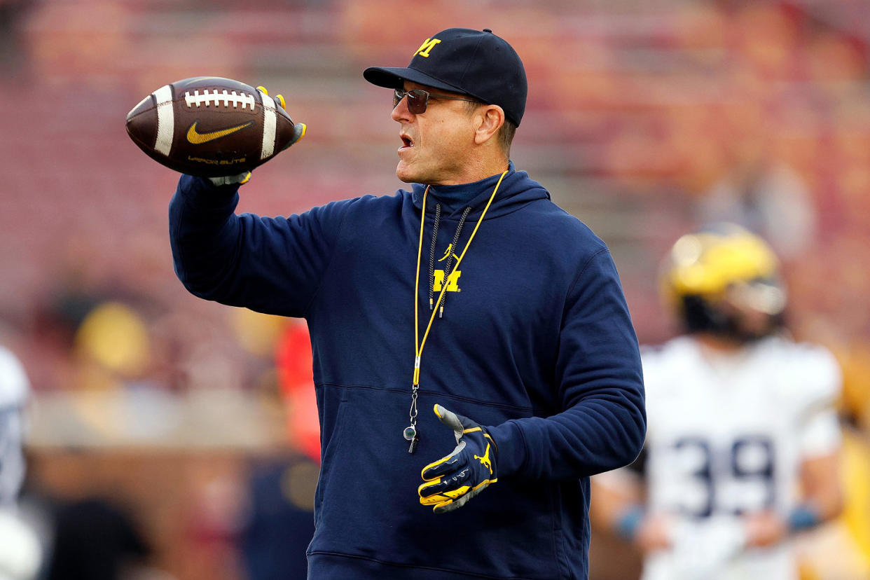 Harbaugh holds a football prior to the start of the game. (David Berding / Getty Images)
