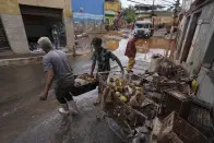 Residentes remove damaged belongings and spoiled food outside their home after flooding in Raposos, Minas Gerais state, Brazil, Tuesday, Jan. 11, 2022. Landslides have killed at least 12 people since the weekend in Brazil's Minas Gerais state, which has been pummeled by intense rainfall, and authorities are monitoring dams that could burst. (AP Photo/Eugenio Savio)