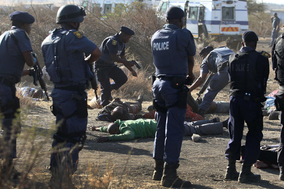 Police surround the bodies of striking miners after opening fire on a crowd at the Lonmin Platinum Mine near Rustenburg, South Africa, Thursday, Aug. 16, 2012. South African police opened fire Thursday on a crowd of striking workers at a platinum mine, leaving an unknown number of people injured and possibly dead. Motionless bodies lay on the ground in pools of blood. (AP Photo)